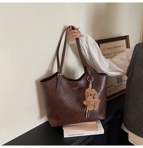 Close-up of vintage brown tote bag with leather texture and cute plush bear accessory