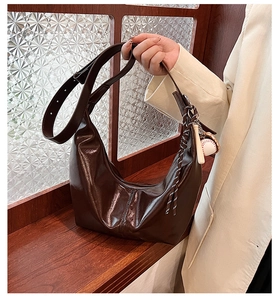 Detail of dark brown glossy hobo bag with baseball charm and wide strap