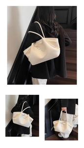 Detail view of large beige leather tote bag with lychee texture and gold buckle