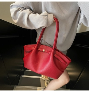 Close-up of red lychee pattern leather tote bag with metallic clasp and long shoulder strap