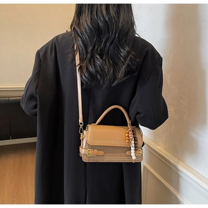 Detail of vintage brown leather handbag with beads charm on a model in black suit