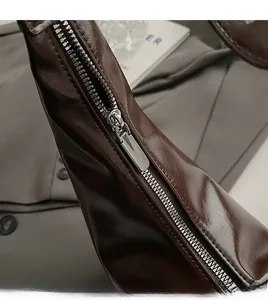 Detail of smooth silver zipper on dark brown vintage leather dumpling bag with glossy finish