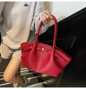 Detail of red pebble leather tote featuring golden metal buckle and decorative bow