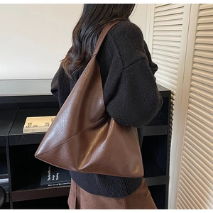 Side view of a large brown vintage hobo shoulder bag shown on a model in a home setting