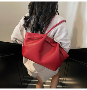 Detail of red lychee pattern leather tote bag with soft texture and adjustable side buckles