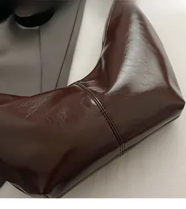 Detail of a dark brown glossy vintage handbag with leather texture and stitching