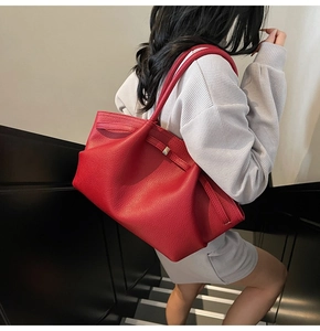 Detail of red pebbled leather tote bag with silver buckle and belt decoration