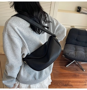 Dettaglio borsa a mezzaluna nera in pelle martellata con fibbie dorate eleganti