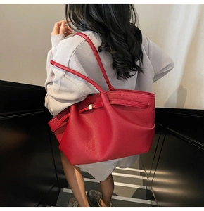 Detail of dark red lychee grain leather tote bag with unique side pleats and shoulder strap