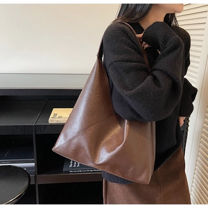 Detail of vintage brown tote bag with wrinkled leather texture on a model's shoulder