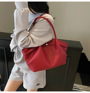 Close-up of deep red leather shoulder bag with lychee texture and metal buckle detail