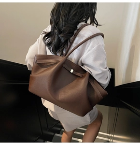 Close-up of a large dark brown lychee leather tote bag with stylish gold metal buckles
