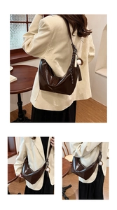 Detail view of a vintage dark brown crescent bag with polished leather and baseball charm