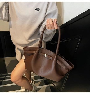 Close-up of a dark brown pebble leather tote bag with elegant folds and gold buckle detail