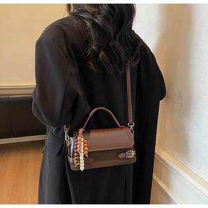 Deep brown vintage frosted crossbody bag with wooden bead charm worn by a model
