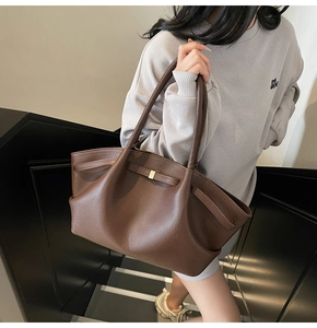 Detail of dark brown lychee pattern tote bag with gold buckle on shoulder of model