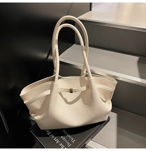Detail of cream white leather tote bag with lychee texture and metal buckle on stairs