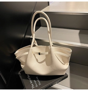 Close-up of off-white tote bag with litchi grain texture on a designer book