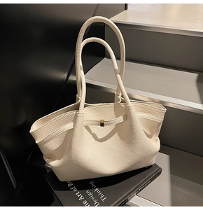Detailed view of the creamy beige lychee textured leather tote bag on a modern staircase