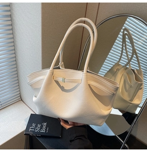 Detail of cream white leather shoulder bag with lychee texture and wing design