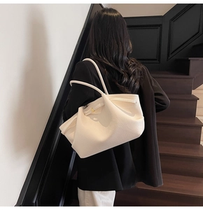Detail of white lychee leather shoulder bag with elegant pleated design and metal buckle