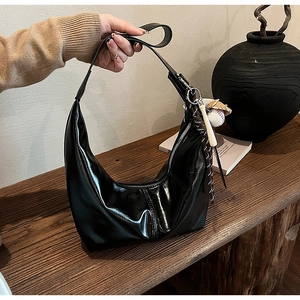 Detail of glossy black hobo bag with unique baseball glove and bat charm accessories