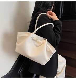 Chic cream white pebble leather tote bag shown on shoulder in a minimalist urban setting