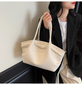 Detail of beige tote bag with lychee pattern leather and elegant gold buckle hardware