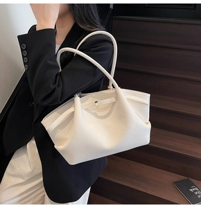 Side view of white lychee pattern tote bag with folding silhouette and slim handles