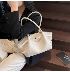 Detail of minimalist cream leather tote bag featuring premium lychee grain and gold clasp