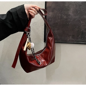Detail of burgundy leather crescent bag featuring baseball glove and bat charms
