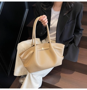 Macro detail of beige lychee grain leather tote bag with elegant gold metal buckle