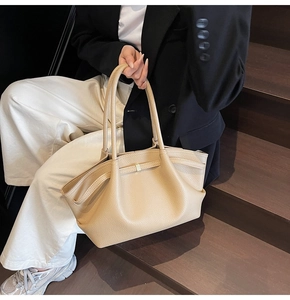 Close-up of beige leather tote bag featuring a textured finish and chic pleated details