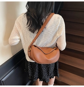 Dettaglio della borsa a mezzaluna in pelle marrone martellata indossata da una modella