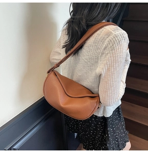 Borsa a mezzaluna marrone in pelle martellata indossata da modella sulle scale