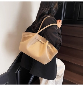Detail of khaki leather tote bag featuring a decorative strap and gold buckle closure