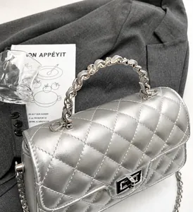 Détail du sac à rabat matelassé argenté avec poignée chaîne et fermoir tournant