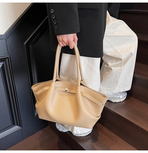 Detail of beige lychee grain tote bag with folded wing structure and metal buckle