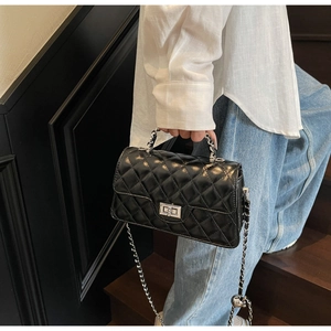 Détail du sac à main en cuir matelassé noir avec fermoir argenté et bandoulière chaîne