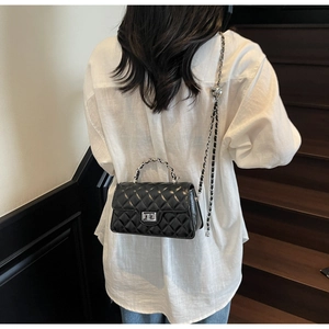 Détails de la bandoulière chaîne argentée et boucle réglable sur sac matelassé noir