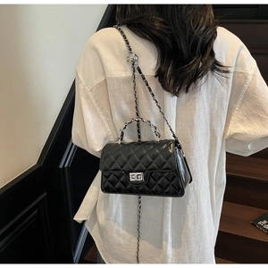 Détail du sac bandoulière en cuir noir matelassé avec fermoir argenté et bandoulière chaîne