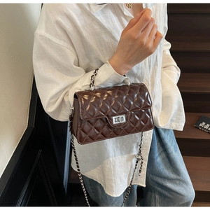 Détail du sac en cuir matelassé marron foncé avec fermoir rotatif argenté et chaîne