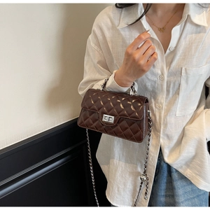 Détail du sac matelassé marron foncé avec fermoir rotatif argenté et bandoulière chaîne
