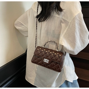 Détail du sac à bandoulière marron foncé matelassé en cuir brillant et chaîne argentée