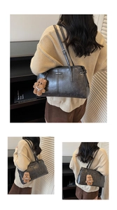 Détail du sac à bandoulière rétro gris foncé avec doubles anses et breloque ours