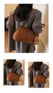 Gros plan du sac en daim marron avec logo en métal et breloque ours en peluche