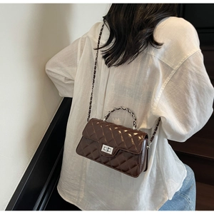 Vue détaillée du sac matelassé marron foncé avec fermoir rotatif argenté et chaîne
