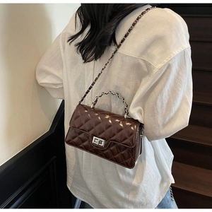 Détail macro d'un sac à bandoulière matelassé marron foncé avec fermoir tournant argenté