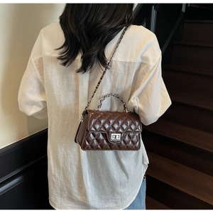 Sac bandoulière matelassé marron foncé avec fermoir rotatif argenté sur modèle