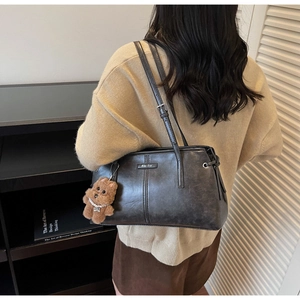 Détail d'un sac porté épaule vintage gris foncé en similicuir avec charme ours en peluche